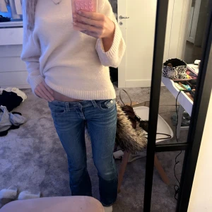 Blå bootcut jeans Gina - Säljer ett par blå jeans med bootcut-modell och låg midja. Jeansen har snygga broderade detaljer på bakfickorna och klassisk femficksdesign. Perfekta för dig som gillar en avslappnad men trendig look.