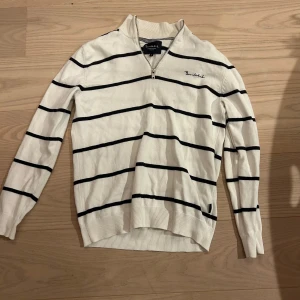 Randig vit tröja från Mq  - Snygg vit långärmad tröja från MQ med mörkblå horisontella ränder och half zip vid halsen. Tröjan har ribbade muddar och klassisk passform, perfekt för en stilren look. Mjuk och skön, passar till många outfits. Den är väldigt bra skick använt men växte ut.