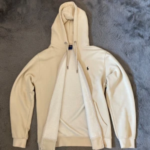 Polo Ralph Lauren Zip Hoddie - Oanvänd Polo Ralph Lauren zip hoodie i storleken L och kommer i Beige färg 