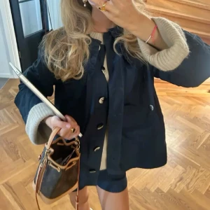 Mörkblå jacka från Ganni💕 - Snygg mörkblå jacka från Ganni med stora knappar och volangdetalj vid kragen. Jackan har en rak passform och är tillverkad i bomull. Perfekt att slänga över en stickad tröja för en chill look. 