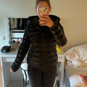 MONCLER BADY DOWN JACKET - Säljer bady down jacket från Moncler.Jackan har en glansig finish, quiltad design och två fickor med dragkedja. Perfekt för kalla dagar och riktigt snygg passform. Se defekter bild 4 & 5. Storlek 14y motsvarar typ storlek 0/1, passar mig bra som är 170cm & S i vanliga fall! Kvitto finns kvar från förra ägaren!