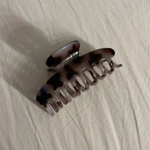 Grå och brun hårklämma - Snygg hårklämma i brun, svart och grå med leopardmönster. Klämman har en rundad form och stark fjäder som håller håret på plats. Perfekt accessoar för att fixa frisyren snabbt och enkelt. Passar både långt och kort hår 🖤🤎🩶