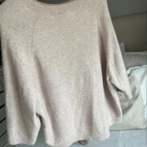 Beige/ljusrosa stickad tröja från & Other Stories - Mysig beige stickad tröja från & Other Stories med rund halsringning och avslappnad passform. Perfekt för lager-på-lager och chill höst- och vinterstil. Enkel att matcha med jeans eller kjol för en clean look.