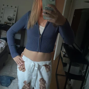 Blå croppad hoodie från Gina Tricot - Säljer en blå croppad hoodie från Gina Tricot med dragkedja framtill. Tröjan har ribbade detaljer vid midjan och ärmarna, samt huva. Perfekt för dig som gillar en trendig och avslappnad stil.