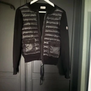 Svart Moncler  cardigan jacka - Säljer vidare min finacardigan jacka som är helt ny, har inte kommit till användning då jag har för många jackor 😇🌸 storlek 1/S. QR kod inuti jacka finns och garanterar äkthet 