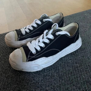 Maison Mihara Yasuhiro svarta sneakers - Unika svarta sneakers från Maison Mihara Yasuhiro med chunky vit sula och kontrasterande vita sömmar. Skorna har breda vita snören, rund tå och detaljer i beige vid tån. Skorna är stor i storlek. Pris kan diskuteras vid snabb affär och kan självklart rengöra dem innan jag skickar