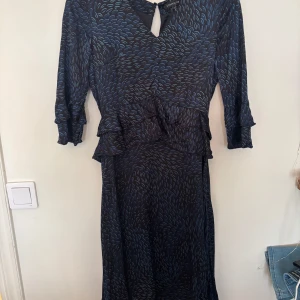 Mörkblå långklänning från STOCKH LM - Säljer en snygg långklänning från STOCKH LM i mörkblått med blått abstrakt mönster. Klänningen har v-ringning, volangdetaljer i midjan och trekvartsärmar. Silkeslent material. Nypris ca 900kr