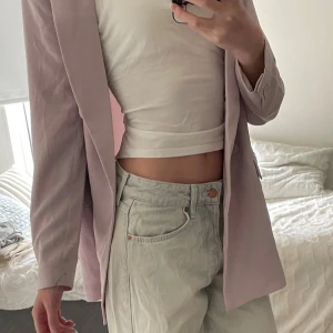 Ljuslila kavaj från H&M, storlek S - Dubbelknäppt kavaj från H&M i en snygg ljuslila färg. Klassisk modell med två framfickor, en liteb slits på baksidan och knappar i samma ton som tyget. Bara använd 1 gång på ett bröllop.  Den har en fläck vid höger ficka som knappt är synlig (sista bilden).