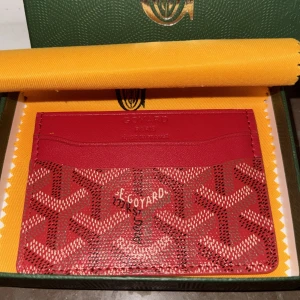  Goyárd plån bok  - Säljer en snygg röd plånbok från Góy árd med deras ikoniska grafiska mönster i vitt och svart. Plånboken är tunn och smidig, perfekt för kort och sedlar. Tillverkad i skinn och canvas, levereras i original grön ask med gul duk.