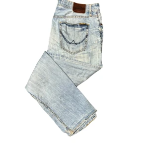 Superdry ljusblå straight fit jeans - Ljusblå jeans från Superdry med loose fit och klassisk femficksdesign. Snygga kontrastsömmar och Superdry-logga på bakfickan. Jeansen har en avslappnad passform och är tillverkade i denim med knäppning fram. Vintage och fadead på ett snyggt sätt.                                                             W34 L32 Pris kan diskuteras