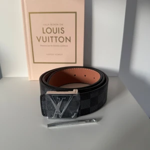  rutig svart bälte - Snyggt bälte med klassiskt spänne i silver. Bältet har ett rutigt mönster i svart och grått, och insidan är beige. Perfekt accessoar för att lyfta din outfit med exklusiv känsla och stil.