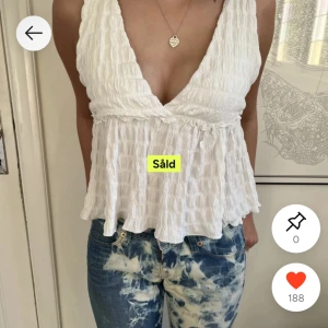 Vit omlott blus med v-ringning - Superfin vit blus med omlott och djup v-ringning. Toppen har en lätt rynkad struktur och volangig nederkant som ger en luftig känsla. Perfekt till jeans eller kjol för en fräsch look. Hör av er vid frågor!