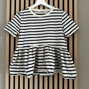 Randig volangblus från Zara - Superfin blus från Zara i vitt och marinblått med klassiskt randigt mönster. Modellen har korta ärmar, rund halsringning och en volang nedtill. 💕💕