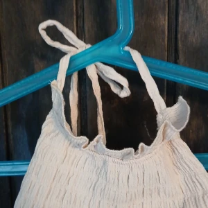 Vit linnetopp med volang från H&M Divided - Supersöt vit linnetopp från H&M Divided i storlek L. Toppen har knytbara axelband, smockad struktur och volangkant nertill. Perfekt för varma dagar och enkel att styla med jeans eller kjol. Materialet är mjukt och luftigt, vilket gör den extra bekväm. Svårt att visa men be om bilder på isf! Köpte för 250 säljer för 130 jag bär s i vanliga fall så passas s/m inte alls för stor!