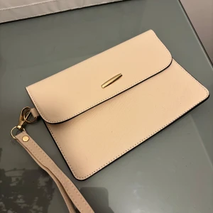 Beige kuvertväska med gulddetalj - Aldrig använd.