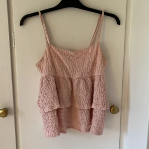 Ljusrosa volangtop från Gina Tricot - Supersöt ljusrosa linnetopp från Gina Tricot med volanger och smala axelband.  den är liten i storleken!! Passar s och xs 