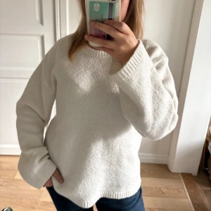 Oversized Vit stickad tröja  - Mysig vit stickad tröja med rund hals och långa ärmar. Tröjan har en avslappnad passform och ribbade muddar vid ärmslut och nederkant. Perfekt för kyliga dagar och enkel att matcha med jeans eller kjol. Tröjan, som man ser på bilden har knottror men borde inte vara ett större problem!
