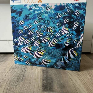 Pussel 1000 bitar - Det här är inte en bok, utan ett pussel med 1000 bitar som visar ett färgstarkt undervattensmotiv med många tropiska fiskar. Perfekt för dig som gillar havet och utmanande pussel! Skapa en cool bild att hänga upp eller lägga om och om igen.