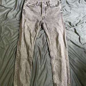 H&M - Säljer ett par grå tvättade relaxed jeans med klassisk femficksdesign och dragkedjegylf. Jeansen har en smal passform och är perfekta för dig som gillar en stilren och enkel look. Materialet är mjukt och följsamt jeans.