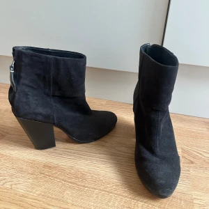 Svarta mocka boots från Rag & Bone - Snygga svarta boots från Rag & Bone i mjuk mocka med spetsig tå och kraftig klack. Dragkedja baktill för enkel påtagning. Perfekta för dig som vill ha en stilren och trendig look med lite edge. Klacken är 9cm