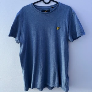 Blå t-shirt från Lyle & Scott - Snygg blå t-shirt från Lyle & Scott med klassisk rund hals och gul broderad logga på bröstet. Skön passform och tillverkad i mjuk bomull, perfekt för en avslappnad stil.