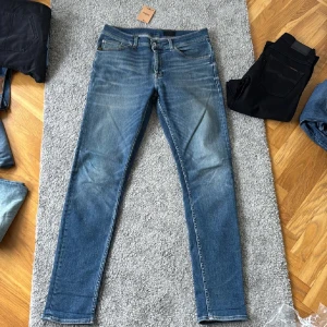 Tiger of Sweden jeans - Snygga blå jeansbyxor från tiger of Sweden med klassisk femficksdesign och bruna kontrastsömmar. Jeansen har en slim passform och raka ben, samt en läderpatch bak i midjan. Perfekta för dig som gillar en stilren och enkel look. Modellen evolve, pris kan diskuteras! Storlek W33 L34 men passar även W32