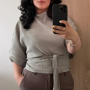 Mint grön topp från Gina Tricot - Säljer en mintgrön topp från Gina Tricot med knytband i midjan och korta vida ärmar. Toppen har ståkrage och ett snyggt vertikalt ribbat mönster som ger en modern look. Perfekt att styla med både jeans och kostymbyxor. Storlek 36, pris 200 kr + frakt. Skriv till mig vid intresse! 