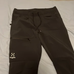 Haglöfs vindbyxor  - Svarta softshellbyxor från Haglöfs i storlek 46. Byxorna har dragsko i midjan, fickor med dragkedja och en stilren logga på benet. Perfekta för utomhusaktiviteter och har en sportig, rak passform. Riktigt bekväma också! Storlek S/M. !!KVITTO FINNS!!