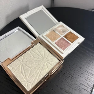 Highlighterpaletter  - Två highlighterpaletter: W7 Ice 'N' Bright med en skimrande ljus puderhighlighter i guldig förpackning och Camilla Pihl Creamy Highlighter Palette med fyra krämiga nyanser i vitt, champagne, rosa och brons. Båda har spegel i locket och stilrena vita fodral.