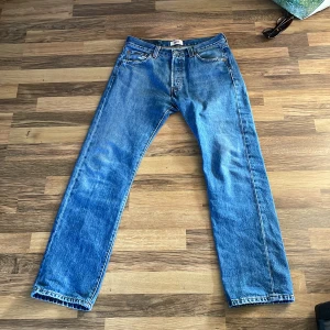 Vintage Levi's 501 blå jeans straight fit - Klassiska blå Levi's 501 jeans med rak passform och fem fickor. Jeansen har knappgylf och är tillverkade i slitstarkt bomullsdenim. Perfekta för dig som gillar en tidlös och avslappnad stil. Är storleken 30/30 på dem