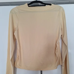 Beige långärmad topp  - En stilren beige långärmad topp med rund halsringning. Perfekt för lager-på-lager eller som den är. Enkel och clean design som passar till det mesta.