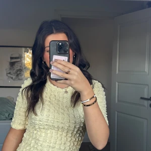 Gul strukturerad topp från Lindex - Superfin ljusgul topp från Lindex med kort ärm och coolt strukturerat tyg. Modellen är rak och har rund halsringning. Perfekt att styla med jeans eller kjol för en fräsch look.