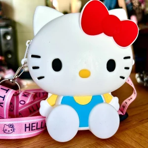Söt liten väska  med Hello Kitty-motiv! - Söt liten väska i silikon med Hello Kitty-motiv och justerbar axelrem med ett fack som stängs med dragkedja. Mått: 13 x 10 cm. Oanvänd.