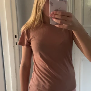 rosa ribbad t-shirt i bomull - Säljer en enkel rosa ribbad t-shirt i mjuk bomull. T-shirten har korta ärmar och en klassisk rund halsringning. Perfekt basplagg med normal passform och stilren look.