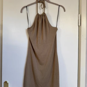 Brunaktig klänning med öppen rygg - Säljer en brunaktig kortklänning från H&M med knyt i nacken. .