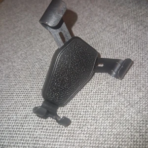 Mobilhållare för bil - Praktisk mobilhållare designad för att fästas i bilens ventilationsgaller för enkel åtkomst och sikt under körning. Passar de flesta telefoner tack vare justerbara klämmor. Funktion: Håller telefonen säkert på plats under körning, vilket möjliggör handsfree-navigering och samtal. Tillverkad av slitstark plast med en texturerad yta för bättre grepp om telefonen.