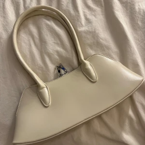 Krämvit handväska  - Snygg och stilren handväska i krämvitt från Gina Tricot. Perfekt storlek för det viktigaste och passar till många olika outfits. Aldrig använt