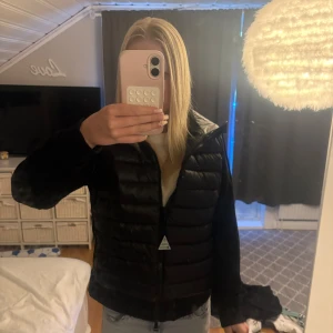 Svart jacka från Moncler - Säljer en svart pufferjacka från Moncler med huva och dragkedja framtill. Jackan har quiltad front, släta ärmar och Moncler-logga på ena ärmen. Perfekt för kyliga dagar och riktigt snygg till jeans.