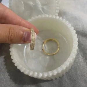 Guldiga creoler med glittriga stenar/ 18 k guldpläterade hoops - Säljer ett par snygga guldiga creoler med glittriga små stenar längs hela framsidan köpta i Turkiet . De är runda och har en klassisk, stilren design som ändå sticker ut tack vare stenarna. Perfekta för dig som gillar lite extra bling i vardagen.