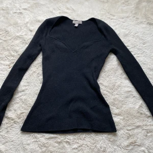Svart ribbad stickad tröja H&M XS - Svart ribbad stickad tröja från H&M i storlek XS. Tröjan har lång ärm, v-ringad hals och figurnära passform. Perfekt att styla med jeans eller kjol för en clean look.