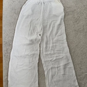 Vita linnebyxor från Gina Tricot strl 36 - Luftiga vita linnebyxor från Gina Tricot i storlek 36. Byxorna har rak passform, resår och snörning i midjan samt är tillverkade i 100% bomull. Perfekta för varma dagar och en chill stil.