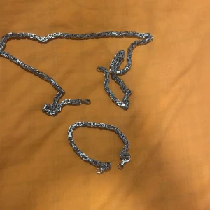 Kedjehalsband och armband i silverfärg - Säljer ett chunky halsband och matchande armband i silverfärgad metall. Båda har robusta länkar och karbinhake som lås. Perfekt för dig som gillar en edgy och modern stil. Snyggt att bära tillsammans eller var för sig.