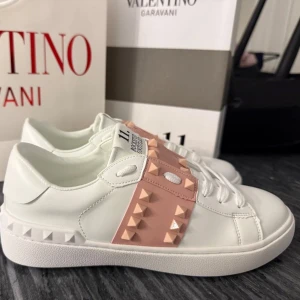 Valentino sneakers - Supersnygga Valentino sneakers i storlek 37! Klassiska vita med fräsch rosa detalj som gör dem både lyxiga och trendiga. Passar perfekt till både jeans och klänning. I toppskick! 👌 