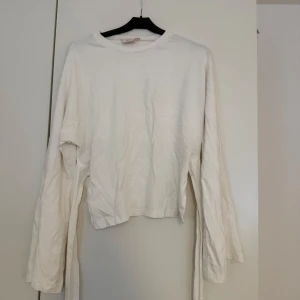 Vit långärmad tröja med snörning Nelly - Säljer en vit långärmad tröja från Nelly i bomull med coola snörningsdetaljer i sidorna. Tröjan har en avslappnad passform och rund halsringning, perfekt för en clean och stilren look.