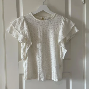 Spetsblus med volang ärmar - Vit blus i spets material och korta volang ärmar. Mycket fint skick och säljes pga att den är för liten och inte kommer till användning!💛💛💛