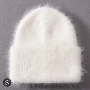 Vit fluffig stickad mössa - Supermjuk och fluffig vit mössa med bred uppvikt kant. Perfekt för kalla dagar och ger en mysig vibe till din outfit. Tillverkad i stickat material med en lätt luddig yta som känns extra cozy.