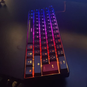 NOS CA250 RGB Mekaniskt Tangentbord - Snyggt och kompakt NOS CA250 mekaniskt tangentbord med RGB-belysning. Flera färglägen, nordisk layout och röda accenter på vissa tangenter. Tangentbordet är i mycket gott skick utan synligt slitage. Perfekt för gaming eller arbete.