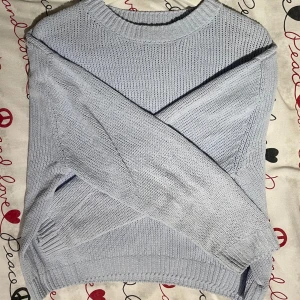 Ljusblå stickad tröja - En stilren ljusblå stickad tröja med rund halsringning och ribbade muddar. Tröjan har en klassisk passform och är perfekt för lager-på-lager under kyliga dagar. Enkel att matcha med både jeans och kjol.