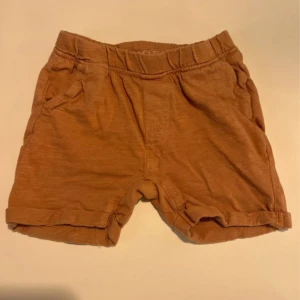 Bruna bomullsshorts från BEBE - Mysiga bruna shorts från BEBE i mjuk bomull med elastisk midja, uppvikta benslut och fickor fram. Perfekta för varma dagar och enkel att matcha med andra plagg.