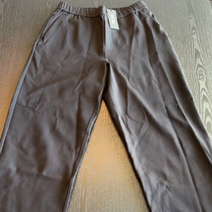 Socrates Pants Wide fit från Something Nothings - Svarta Kostymbyxor från Something Nothings med elastisk midja och raka ben. Sköna och stilrena, perfekta för chill dagar. Tillverkade i mjukt bomullsmaterial för extra komfort.